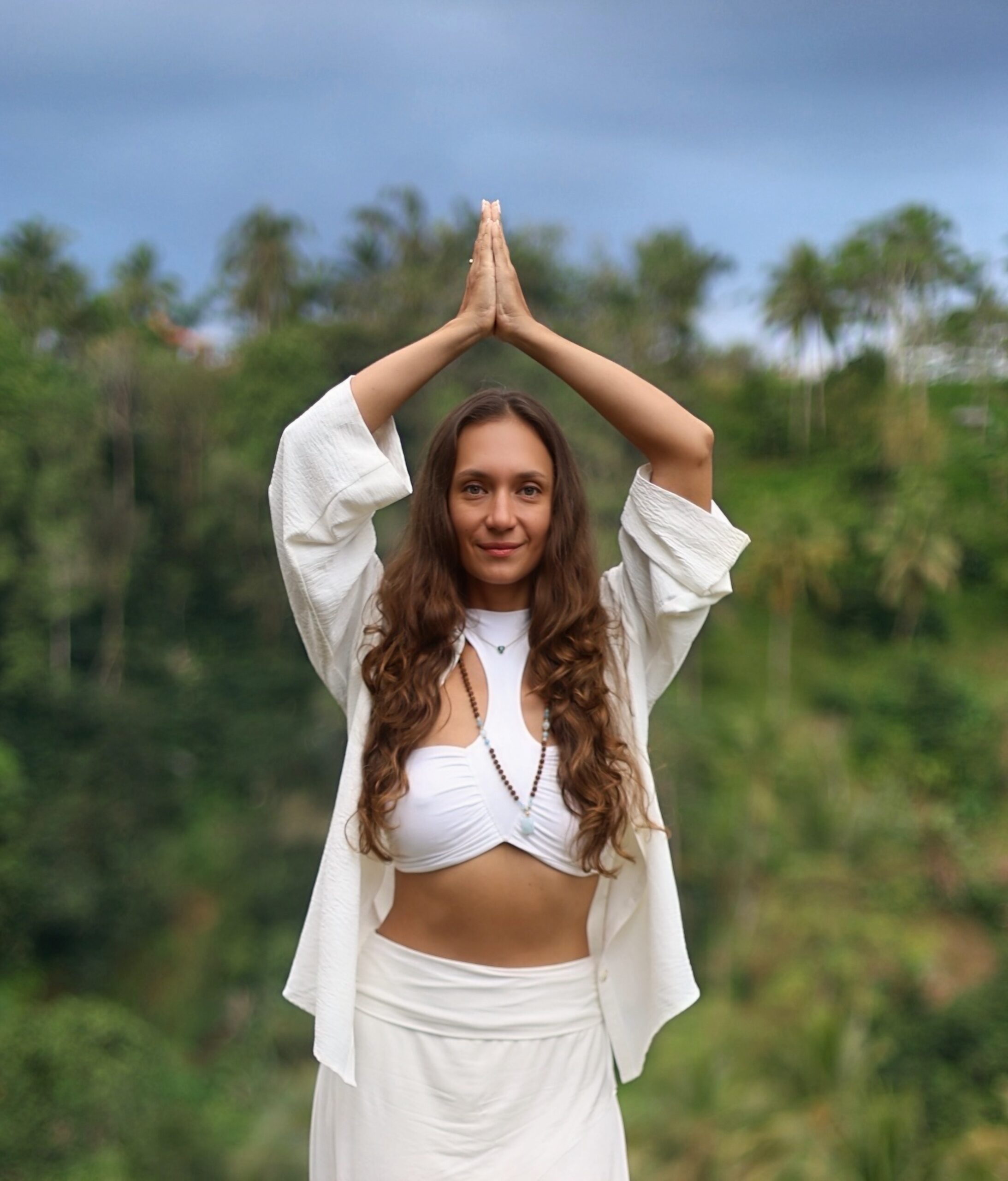 Alena in white with her hands joined above her head